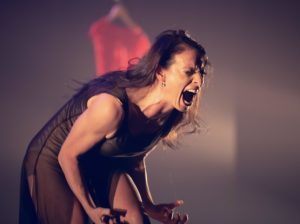 A dancer makes an anguished face and clenches her fists during a performance. 