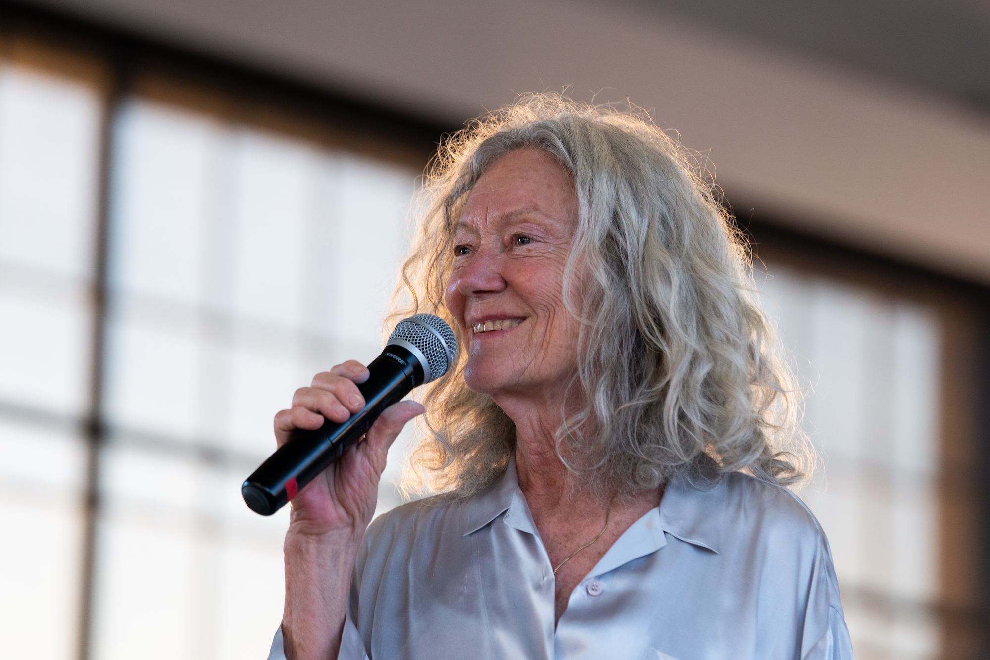 A woman smiling while speaking into a microphone