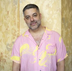 A man posing for a photo in a pink and yellow button up shirt