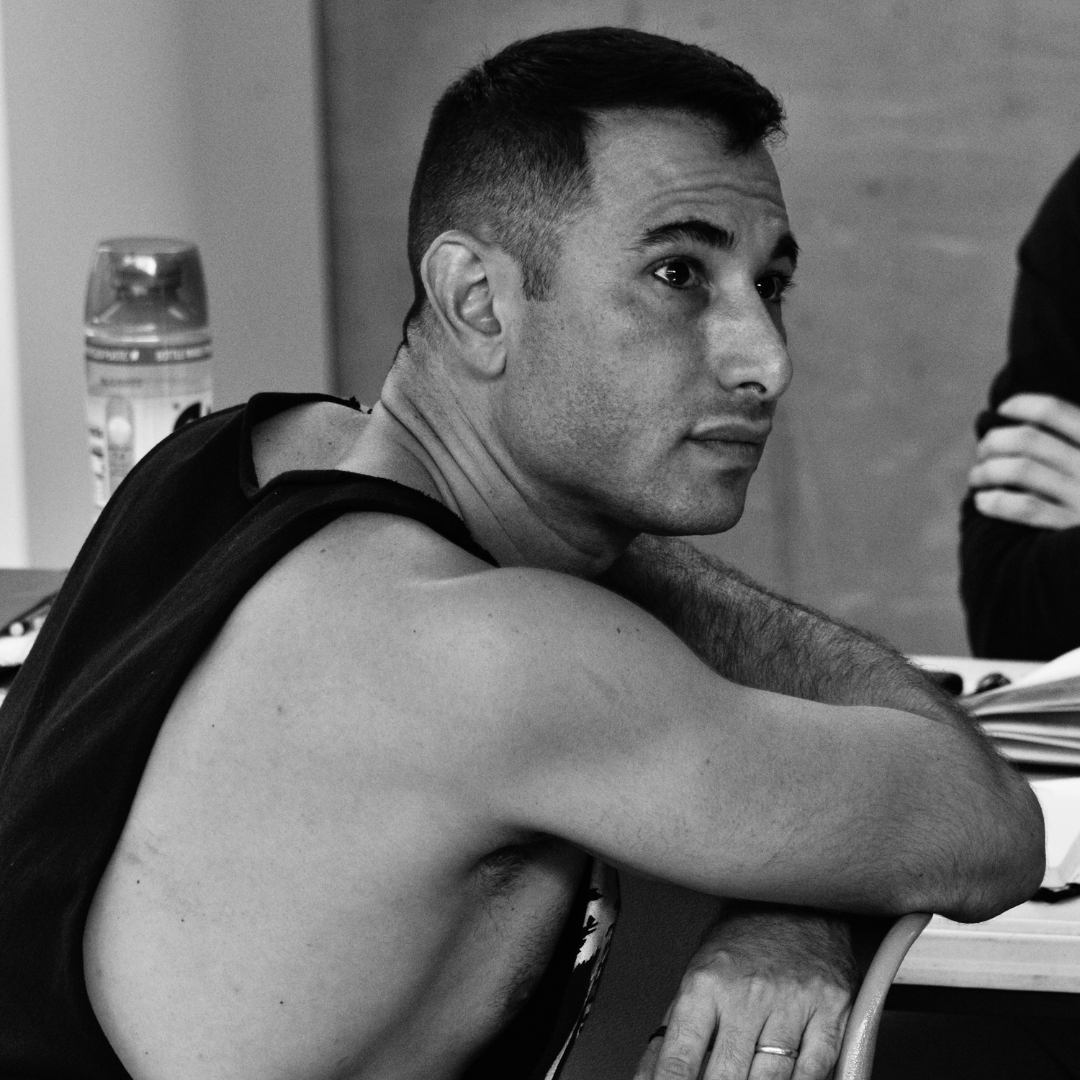 black and white photograph of a man sitting at a table with a laptop